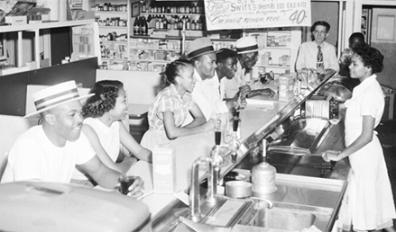 Thrifty Drug Company, one of the first in Dallas to integrate its fountain. African-American customers sitting at the counter being by an african-american employee. 1952